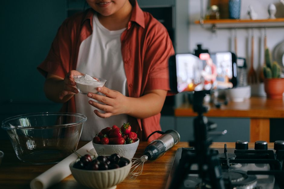 A woman preparing a fruit dessert in a home kitchen, streaming live.