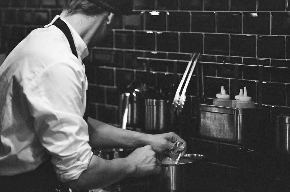 A chef prepares a dish in a stylish kitchen, showcasing culinary expertise.
