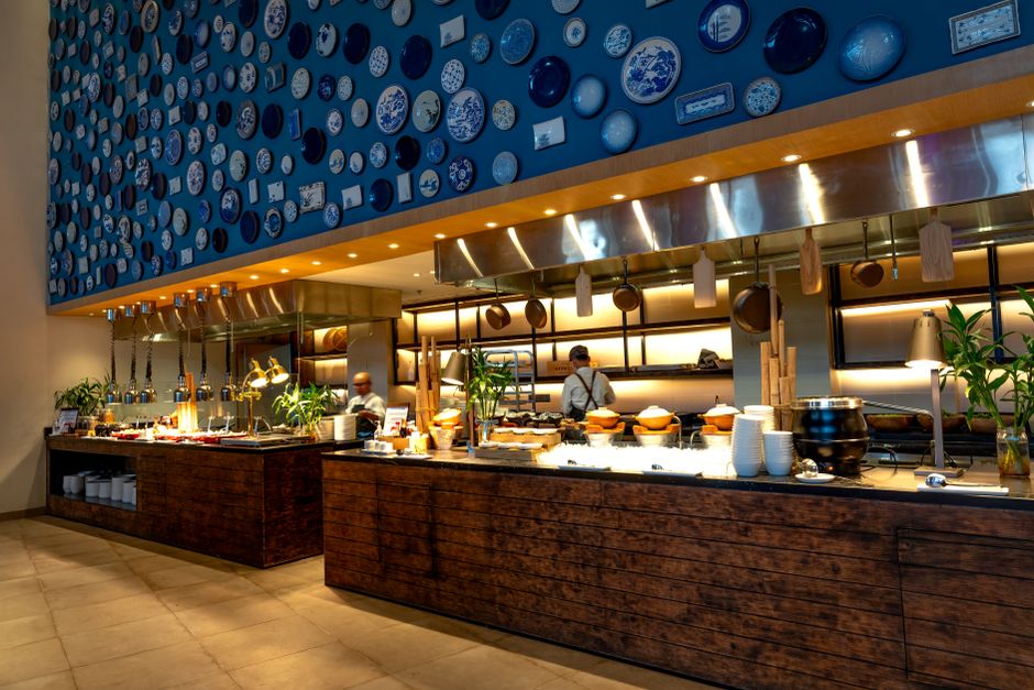 Modern restaurant interior featuring a stylish bar counter and artistic plate wall design.